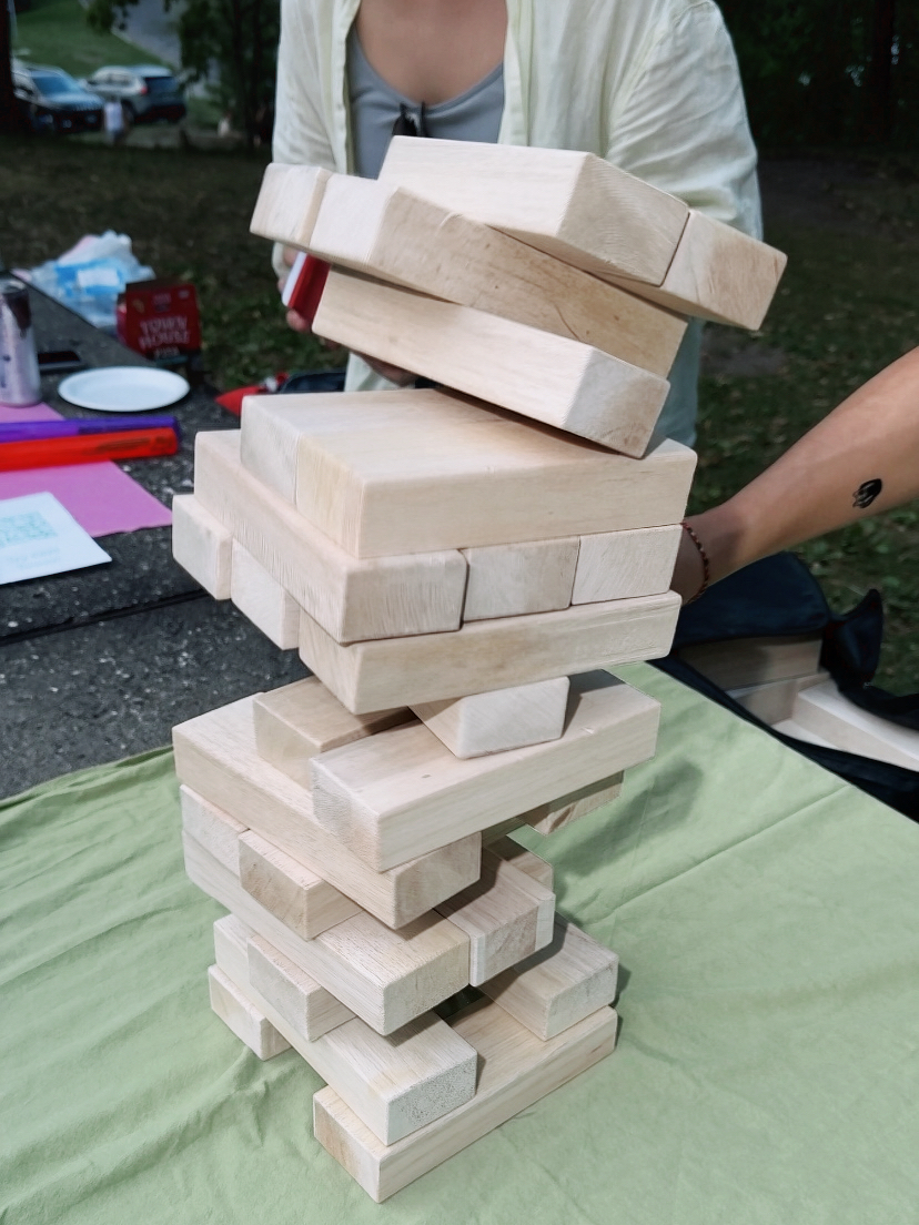 Friends playing a giant stacking game at an OMI park gathering